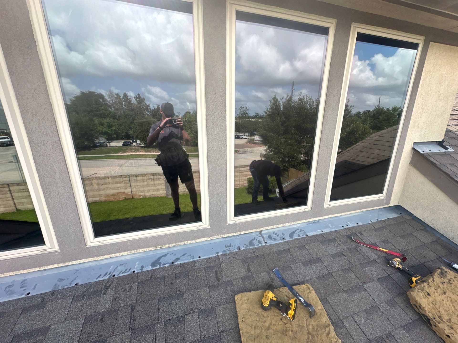 Roof maintenance work in progress, featuring two workers on a rooftop with tools, showcasing EPDM rubber-washered screws and flashing installation.