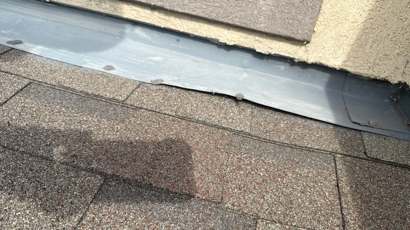Damaged roofing shingles with exposed nails and loose flashing, highlighting potential water intrusion issues and the need for maintenance or repair.
